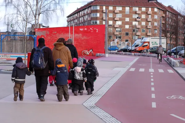 Genitori e bambini camminano lungo una pista ciclabile rossa a Copenaghen