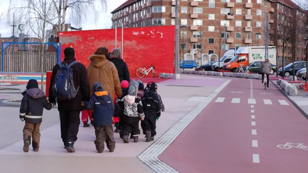 Genitori e bambini camminano lungo una pista ciclabile rossa a Copenaghen