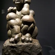 Scultura in bronzo di una figura femminile robusta su roccia in museo