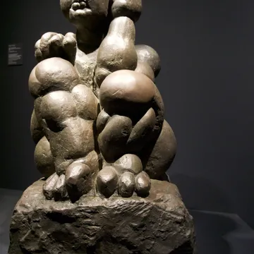 Scultura in bronzo di una figura femminile robusta su roccia in museo