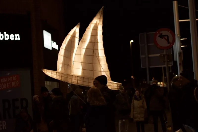 Lanterna luminosa a forma di barca a vela tra la folla notturna ad Århus