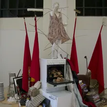 Installazione artistica con figura in abito, bandiere rosse e forno