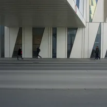 Persone camminano davanti a un edificio bianco con vetrate inclinate a Ørestad