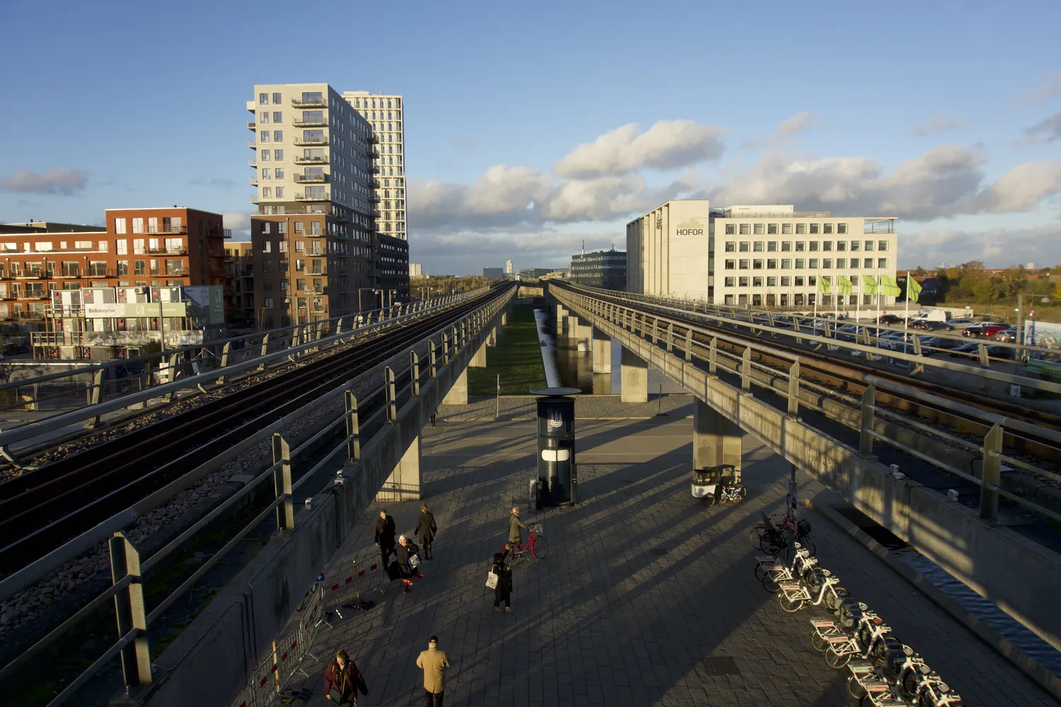Stazione del metro sopraelevata con binari e palazzi moderni a Ørestad