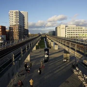 Stazione del metro sopraelevata con binari e palazzi moderni a Ørestad