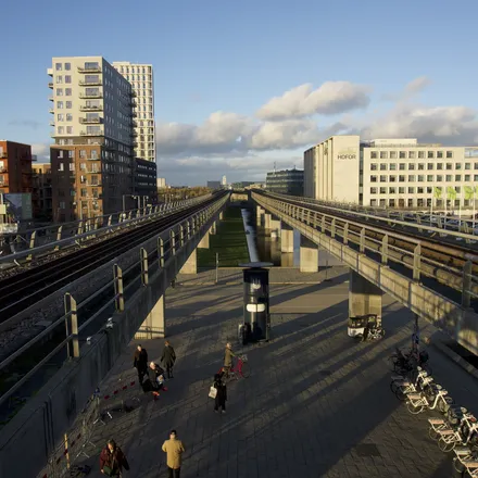 Stazione del metro sopraelevata con binari e palazzi moderni a Ørestad