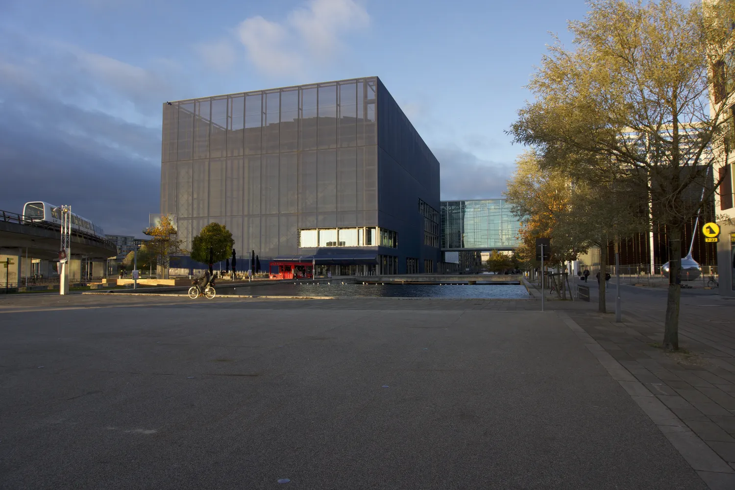 Edificio cubico scuro con facciata traforata accanto a un bacino d'acqua a Ørestad