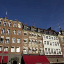 Facciate storiche di palazzi in mattoni con tende rosse a Copenaghen sotto un cielo azzurro