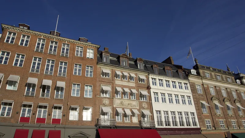 Facciate storiche di palazzi in mattoni con tende rosse a Copenaghen sotto un cielo azzurro