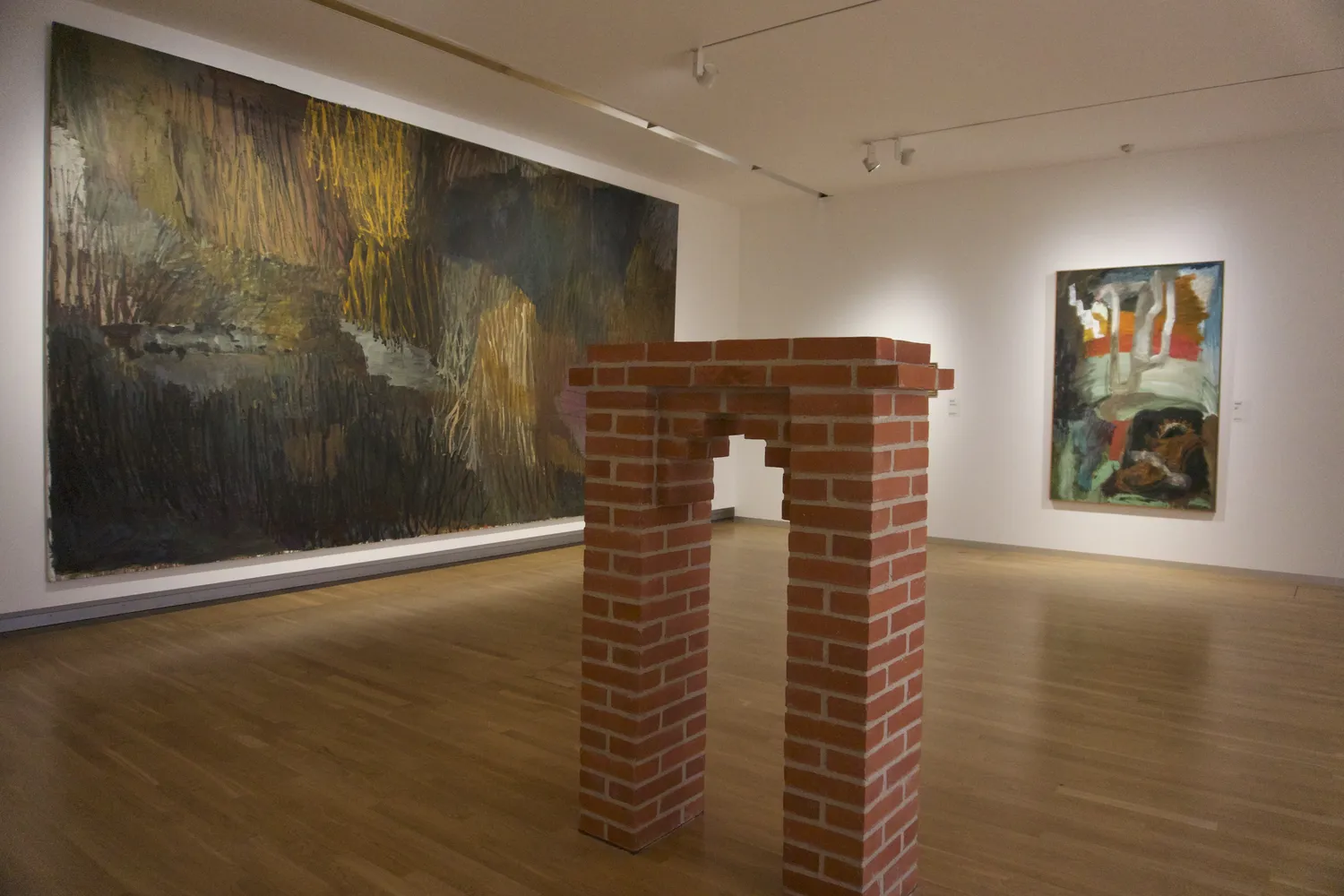 Sala museale con grande dipinto astratto e struttura in mattoni