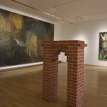 Sala museale con grande dipinto astratto e struttura in mattoni
