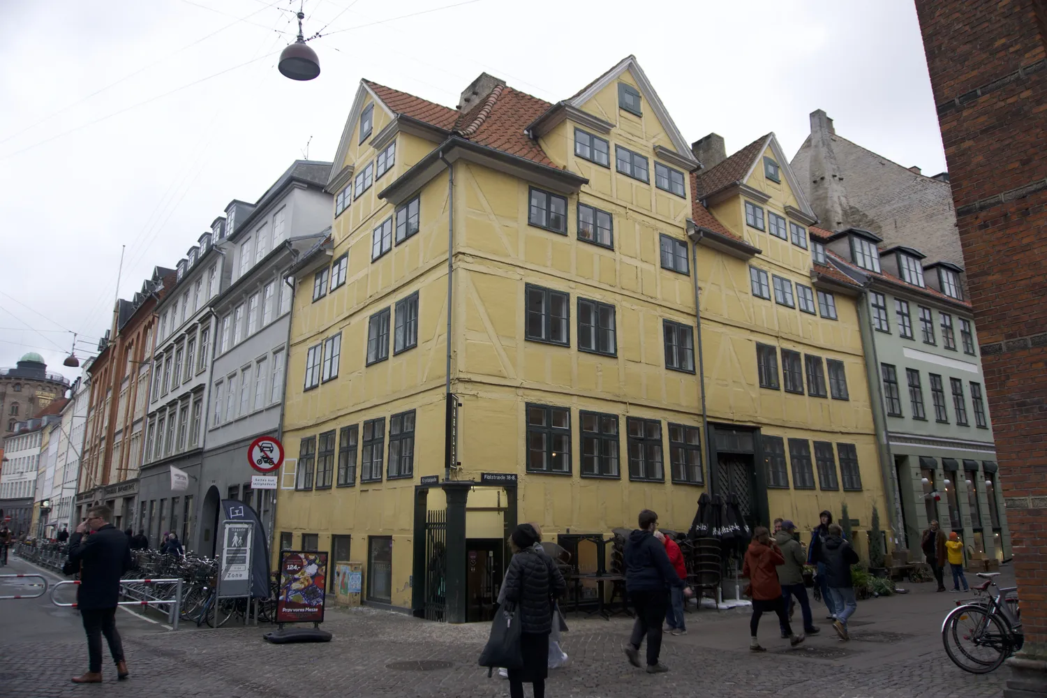 Antico edificio giallo a graticcio su un angolo con passanti