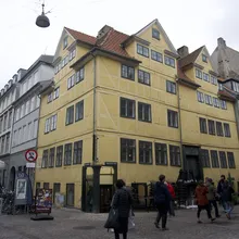 Antico edificio giallo a graticcio su un angolo con passanti