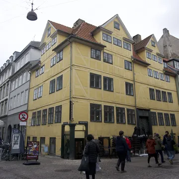 Antico edificio giallo a graticcio su un angolo con passanti