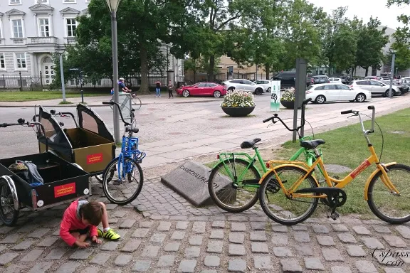 Biciclette colorate e cargo bike parcheggiate su una piazza acciottolata a Copenaghen