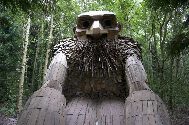 Troll gigante barbuto di legno visto dal basso in un bosco