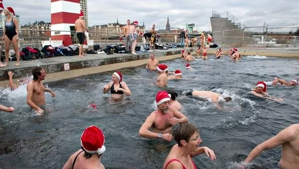 Bagnanti con cappelli di Babbo Natale fanno il bagno invernale a Copenaghen