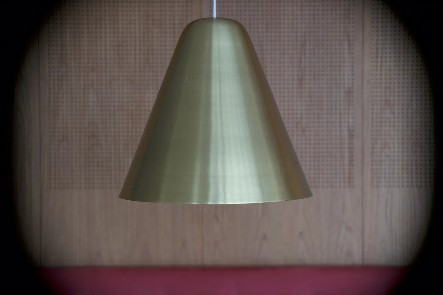 Lampada a sospensione conica in ottone davanti a parete in legno